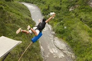 Person bungee jumping over river in green valley